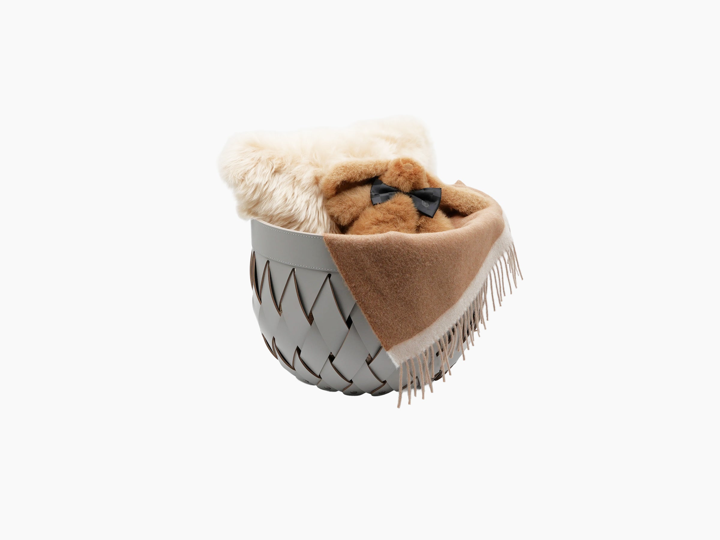 Canaria Small Basket in pale gray braided leather with a brown throw draped over the rim and soft fur inside.