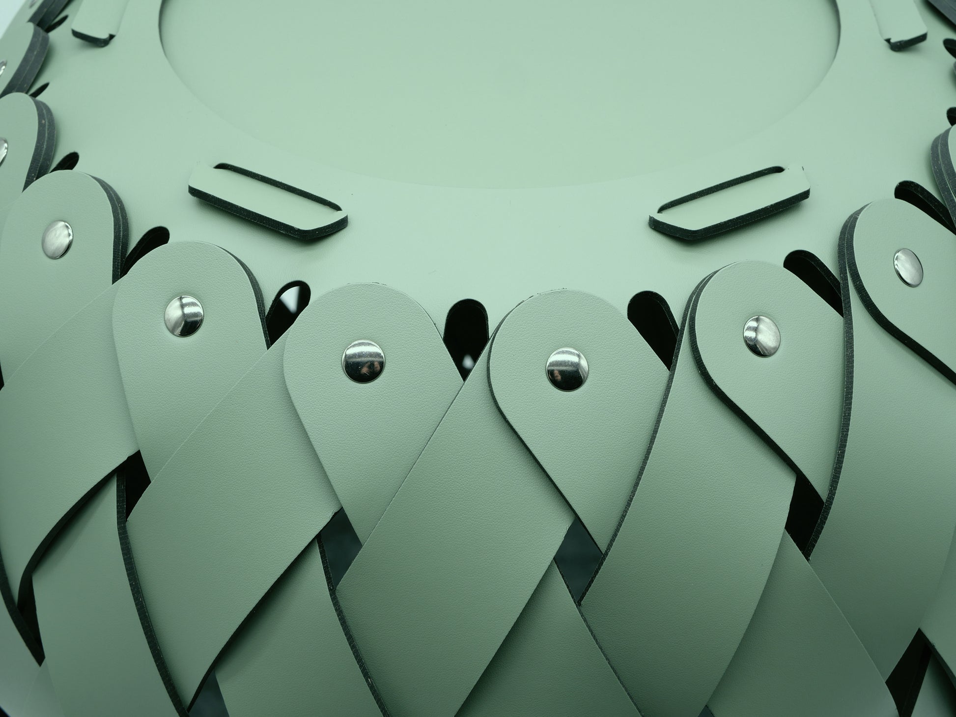 Close-up of green braided Antibes leather strips with metal rivets forming the Canaria basket texture