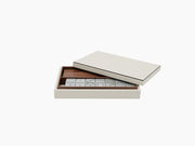 Dominoes set in a leather covered wooden box with white tiles arranged in a polished tray