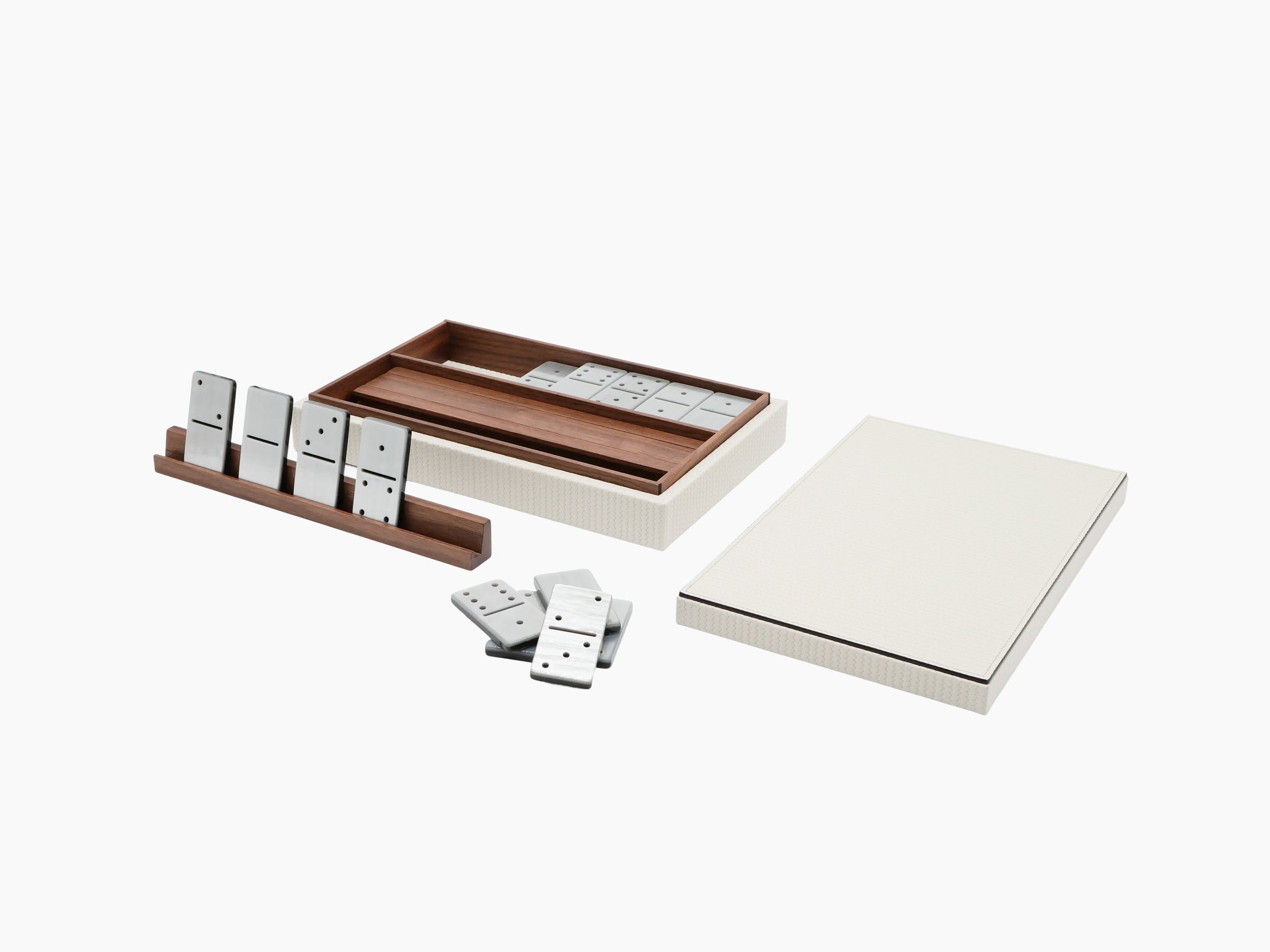 Open leather covered dominoes box with walnut pawn holder and scattered domino tiles beside a cream textured outer box