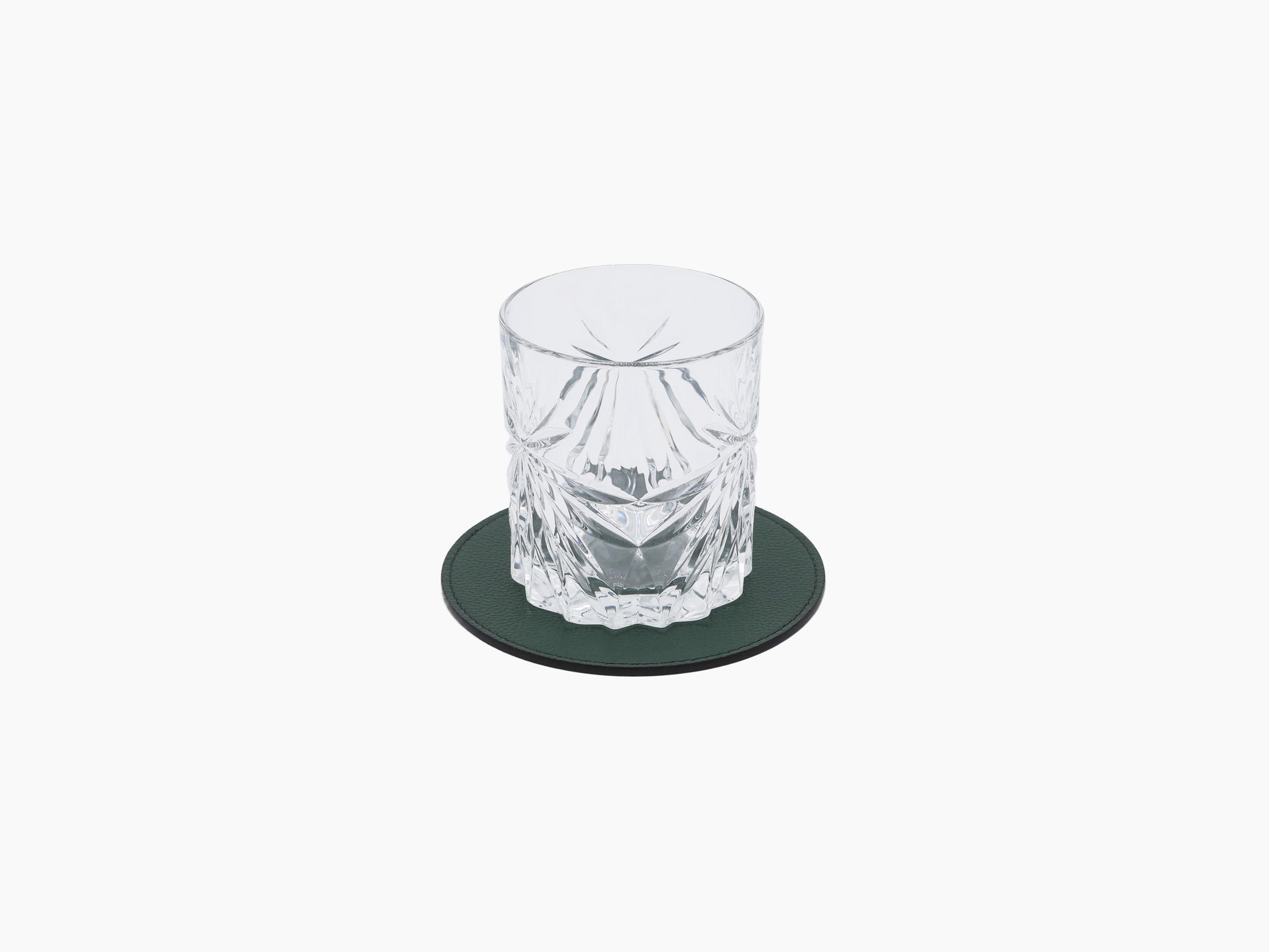 Crystal tumbler on a dark green round leather coaster