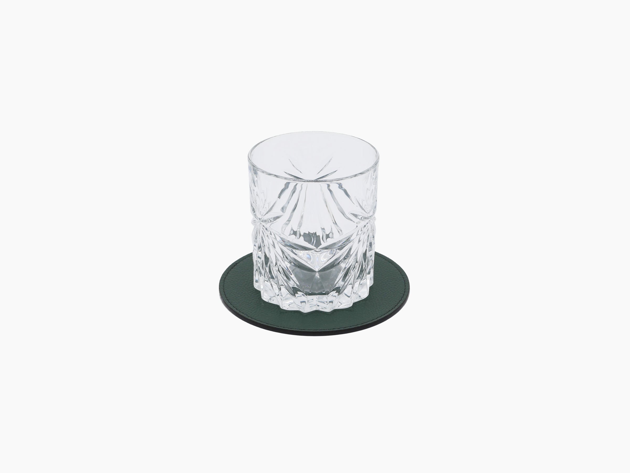 Crystal tumbler on a dark green round leather coaster