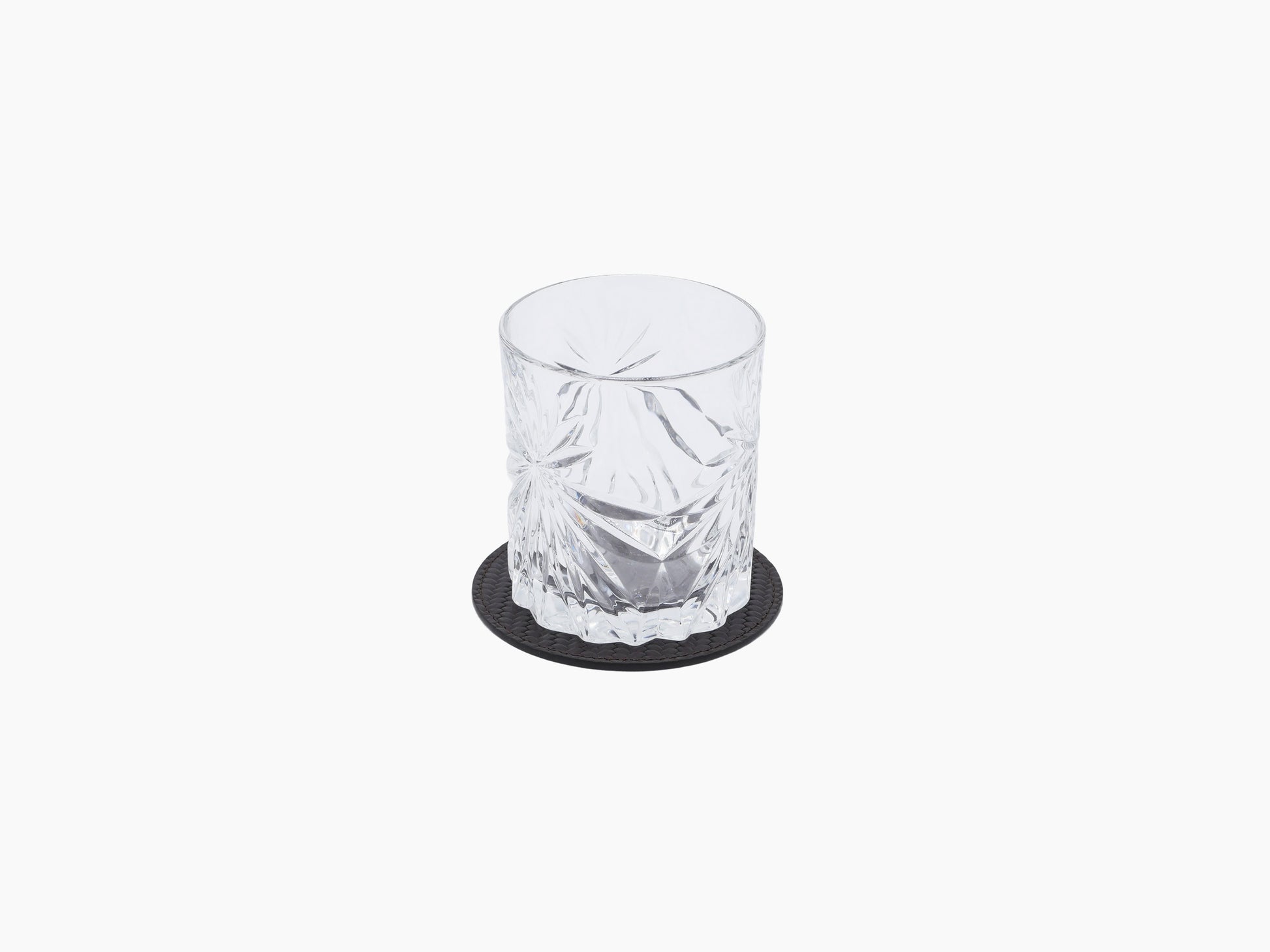 Crystal tumbler on a round leather coaster with a dark leather base