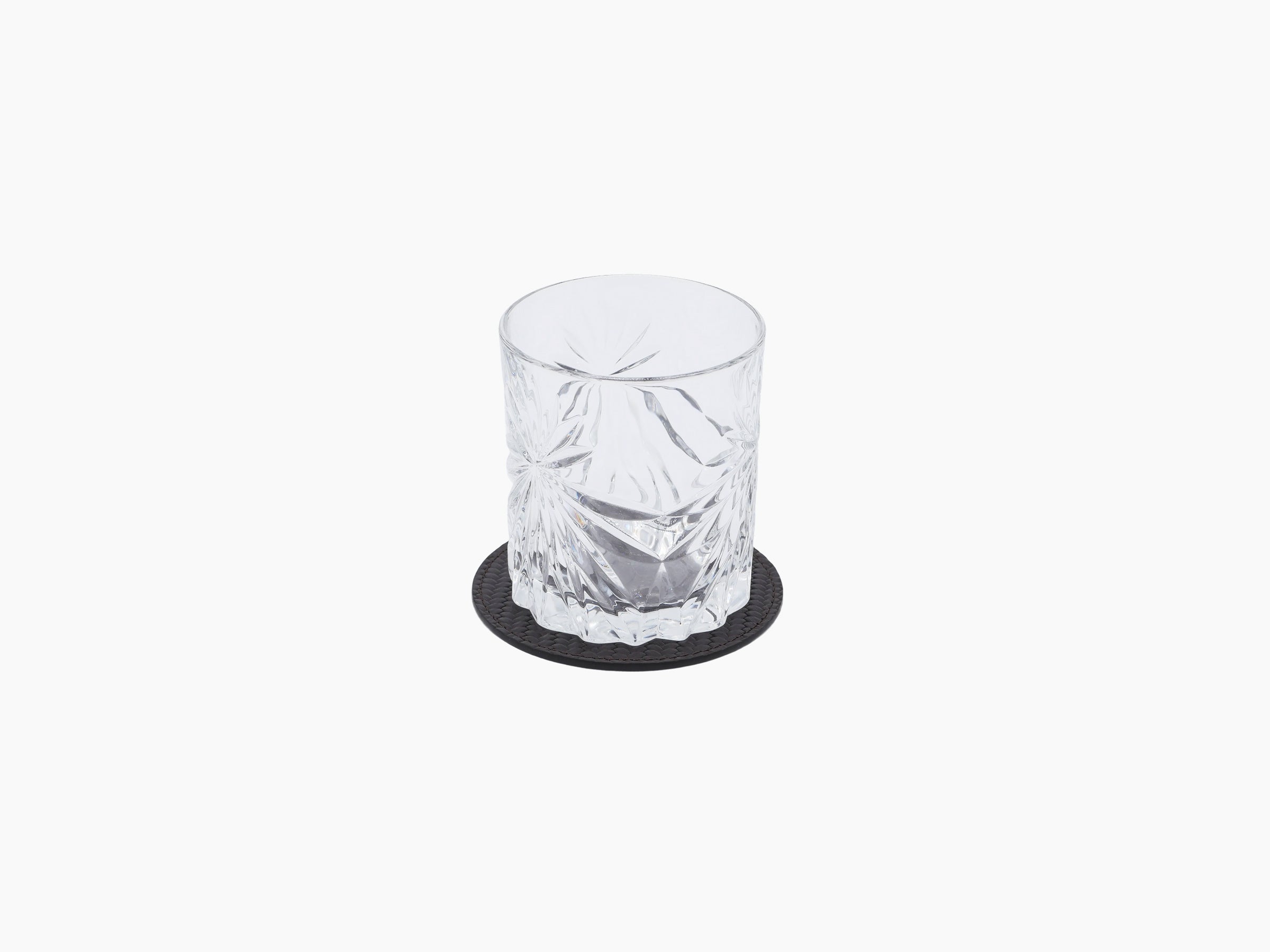 Crystal tumbler on a round leather coaster with a dark leather base