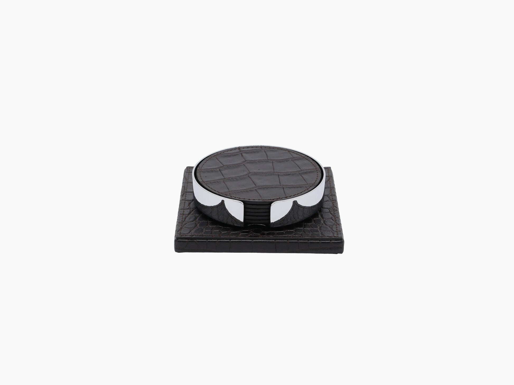 Round leather coaster resting on a chrome framed holder on a dark wooden base