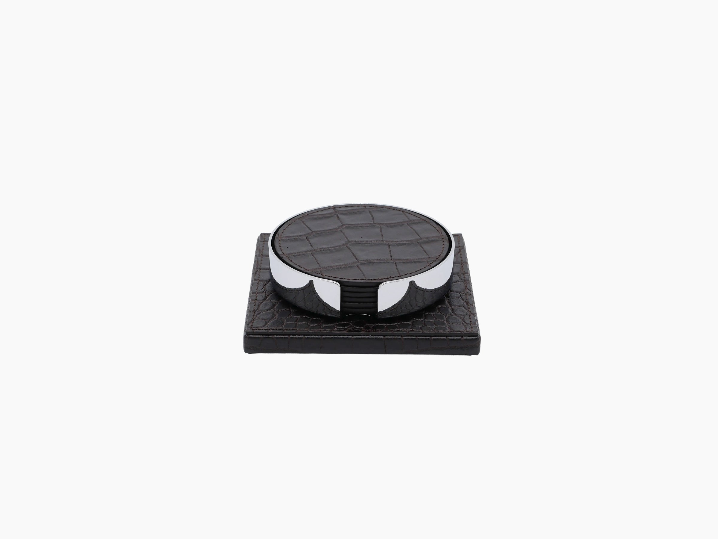 Round leather coaster resting on a chrome framed holder on a dark wooden base
