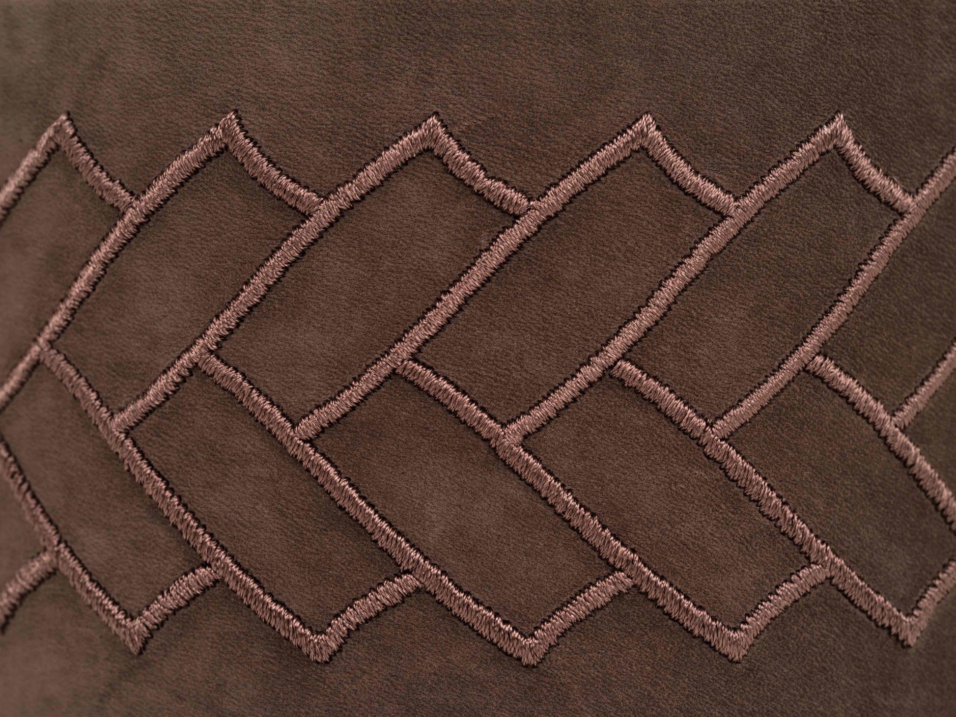 Close-up of brown leather with pink geometric stitching on the Lily box.