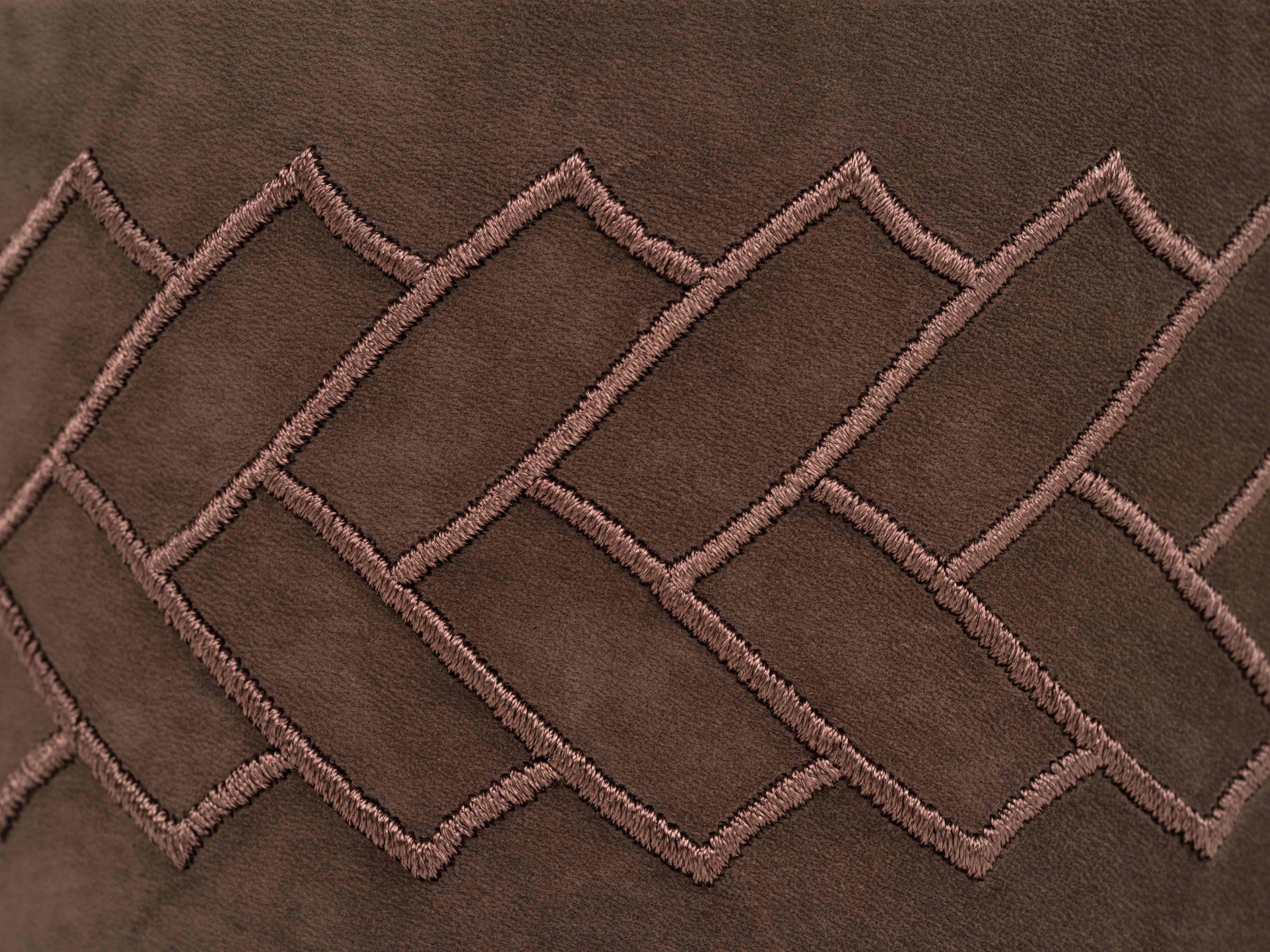 Close-up of brown leather with pink geometric stitching on the Lily box.