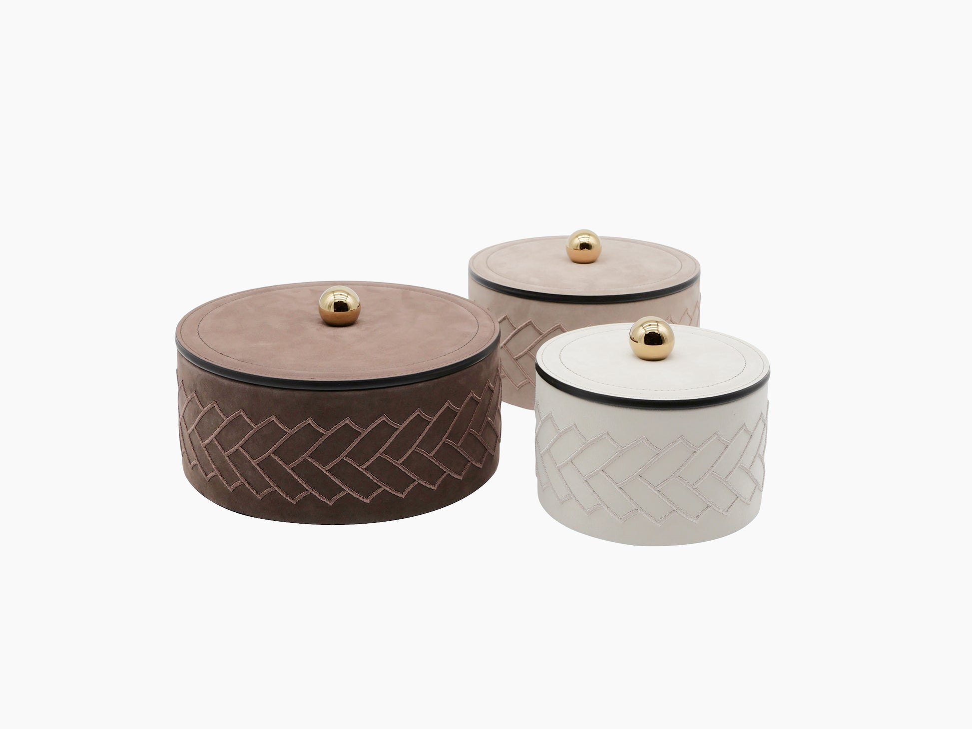 Three round leather jewelry boxes with herringbone stitching and gold knob lids.