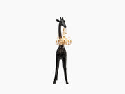 Black Giraffe in Love XS sculpture with a gold Marie-Thérèse style chandelier hanging from its neck against a white background.