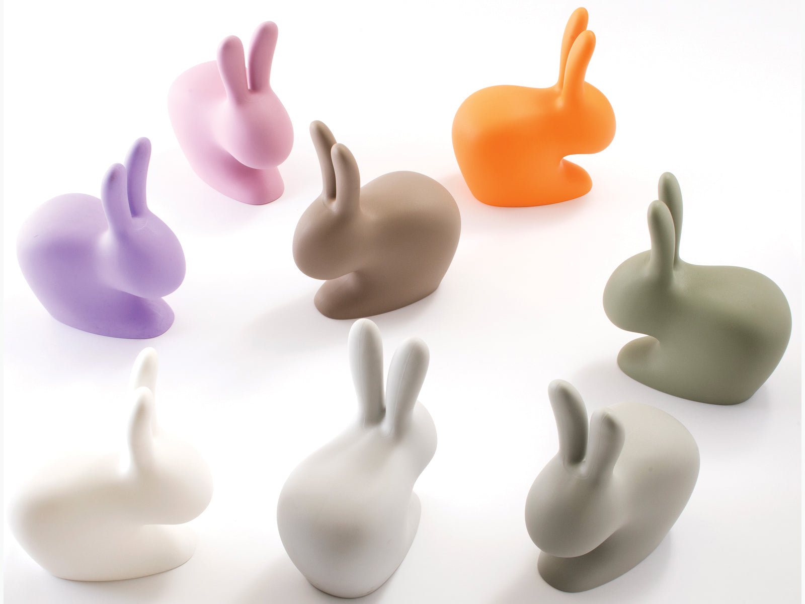 Colorful collection of Baby Rabbit Chairs in pastel shades arranged on a white studio backdrop.