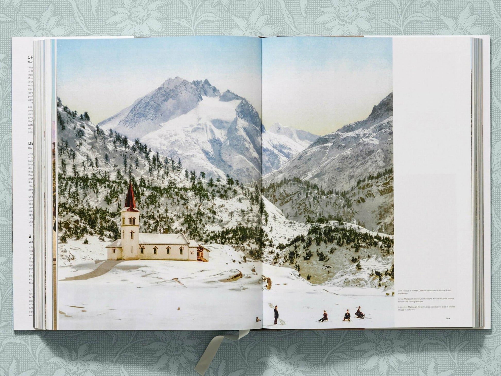 Snowy alpine valley with a church and village set against rugged mountains