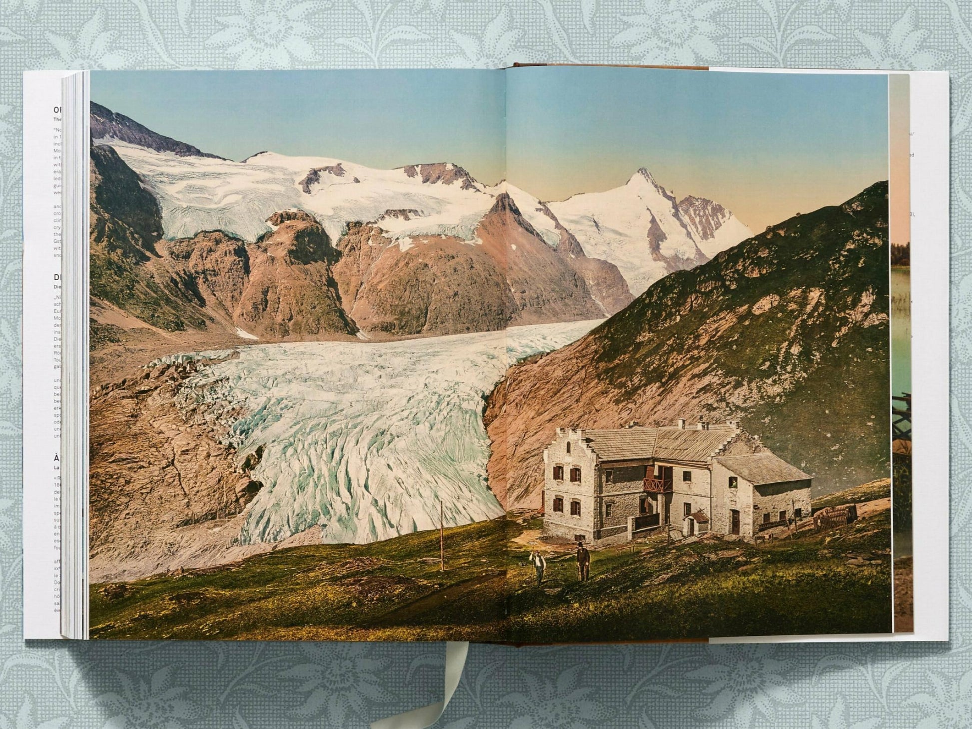 Glacier valley with a stone alpine hut in the foreground and snowcapped peaks in the distance