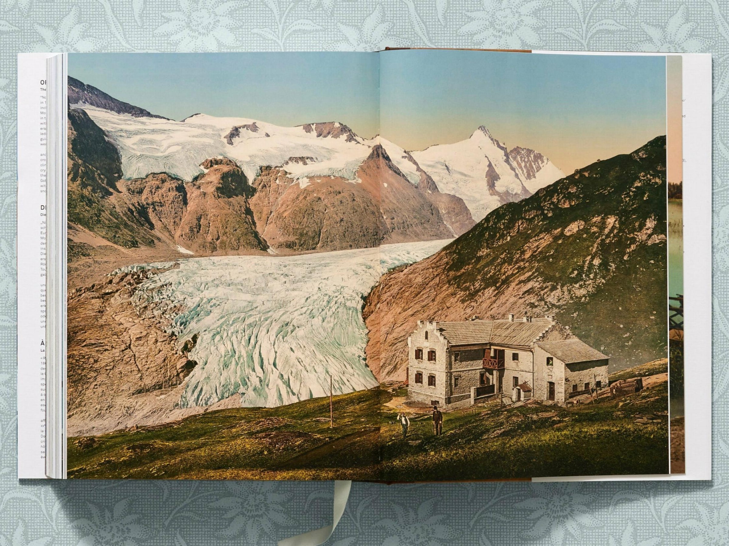 Glacier valley with a stone alpine hut in the foreground and snowcapped peaks in the distance