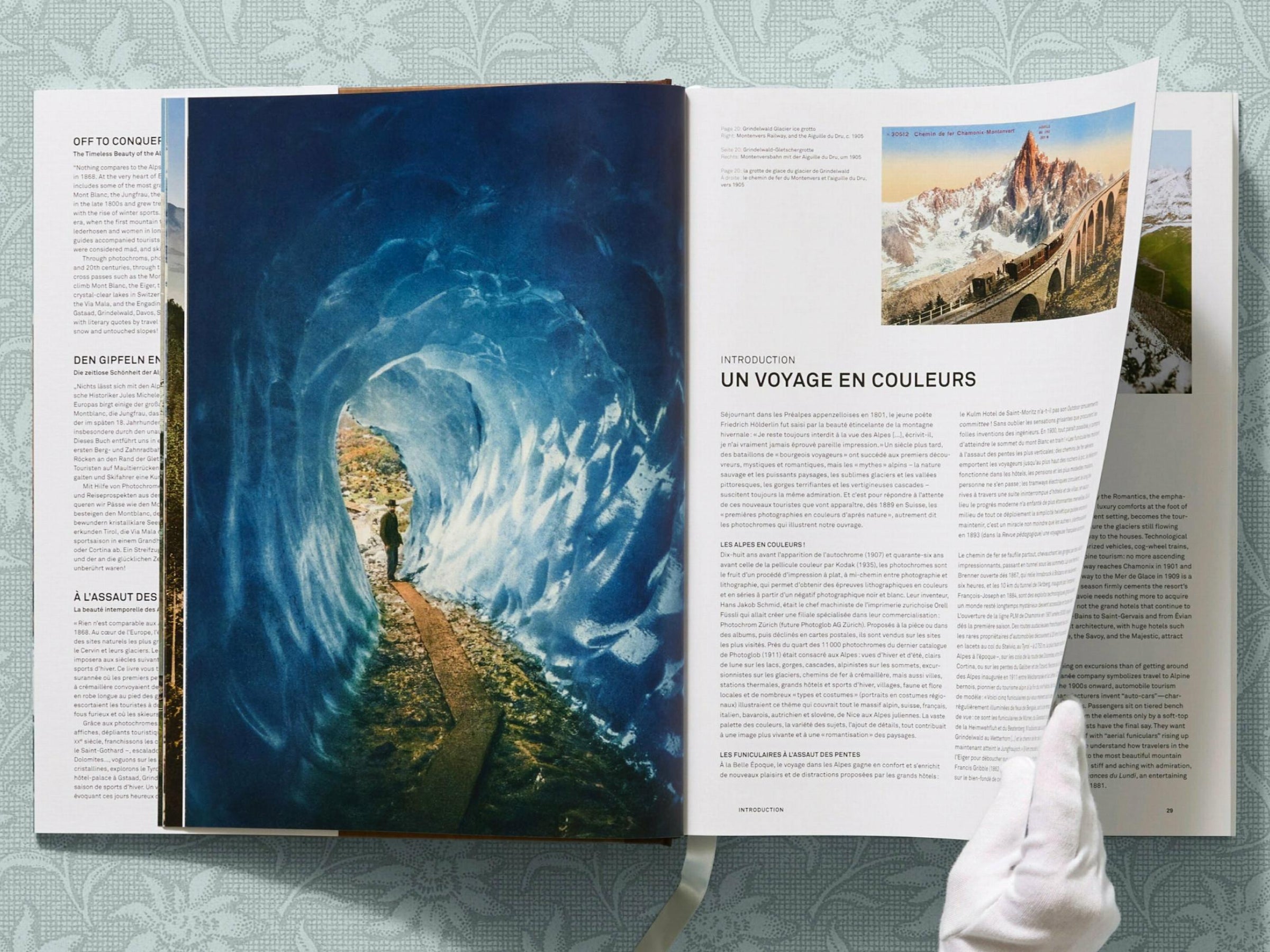 Open book spread showing a blue glacier scene on the left and a white page on the right with a small mountain photo and UN VOYAGE EN COULEURS text