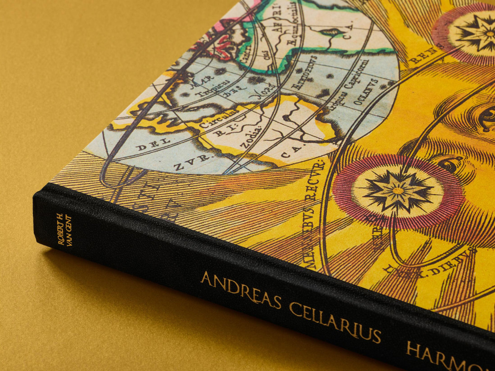 Close up of the Cellarius Atlas book on a gold surface, cover with a celestial map and a black spine with gold Andreas Cellarius text.