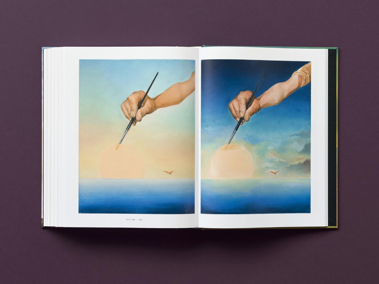 Open Dalí Complete Paintings edition showing a two page spread with a hand holding a brush painting a sun over the sea against a pastel sky.