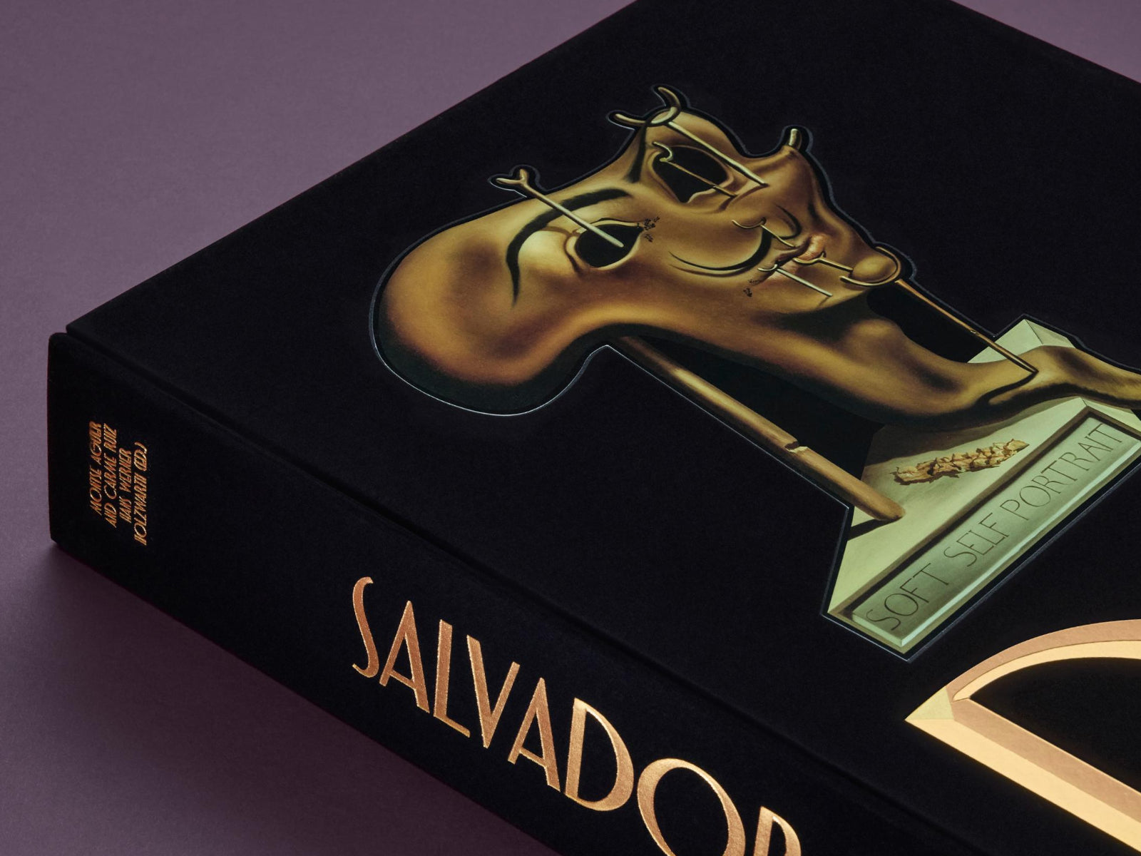 Close-up of a black Dalí book box with a gold embossed surreal sculpture on the cover and Dalí name on the spine.