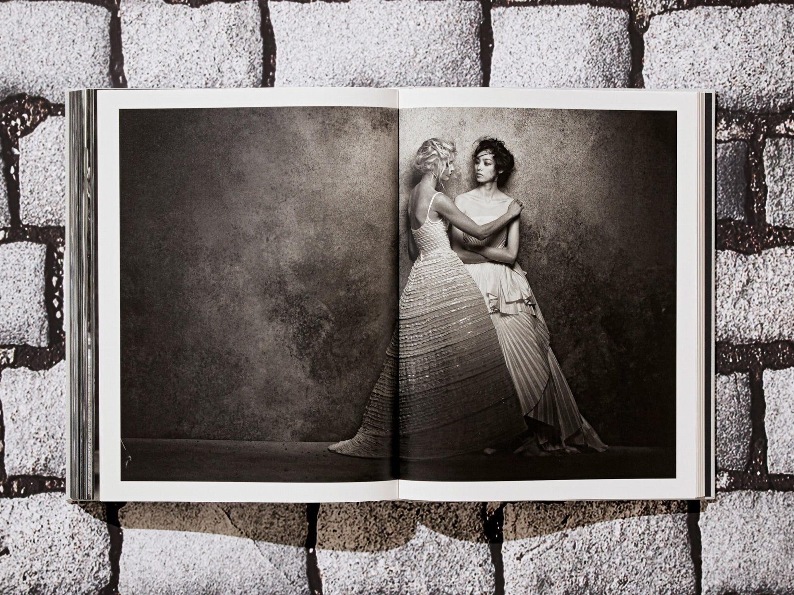 Two models in couture gowns posing for a black-and-white studio photograph across a two-page spread
