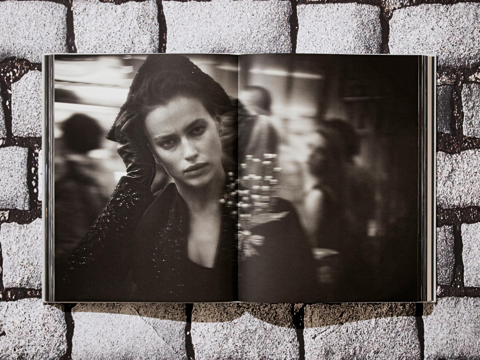 Black-and-white portrait from Peter Lindbergh Dior of a model in a dark sequined dress and gloves, resting a gloved hand on her head in a street scene.
