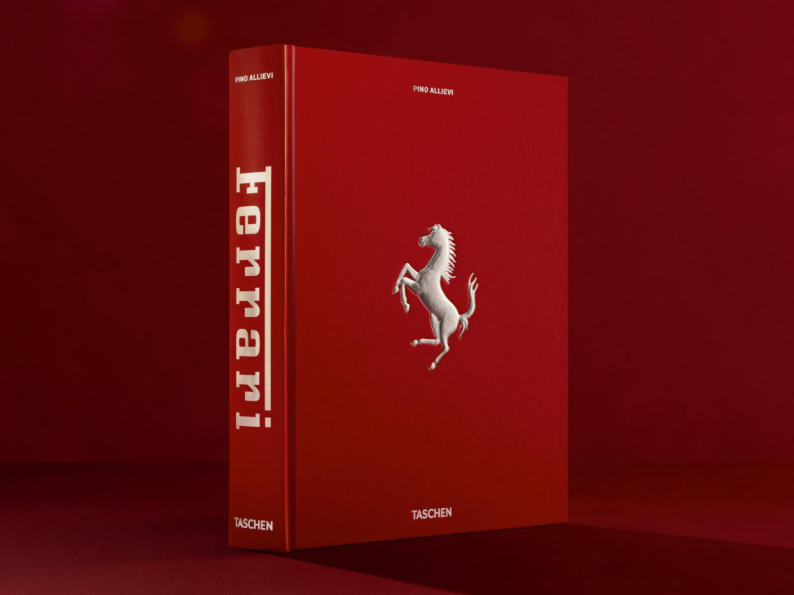Angled view of the red Ferrari book in a studio, bold white Ferrari logo on the spine.