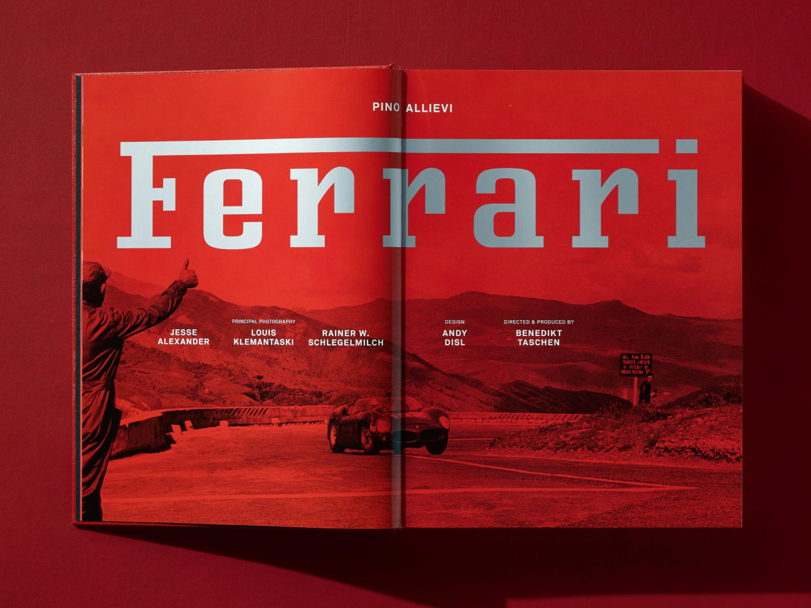 Open red Ferrari book spread with bold white Ferrari typography over a racing photograph.