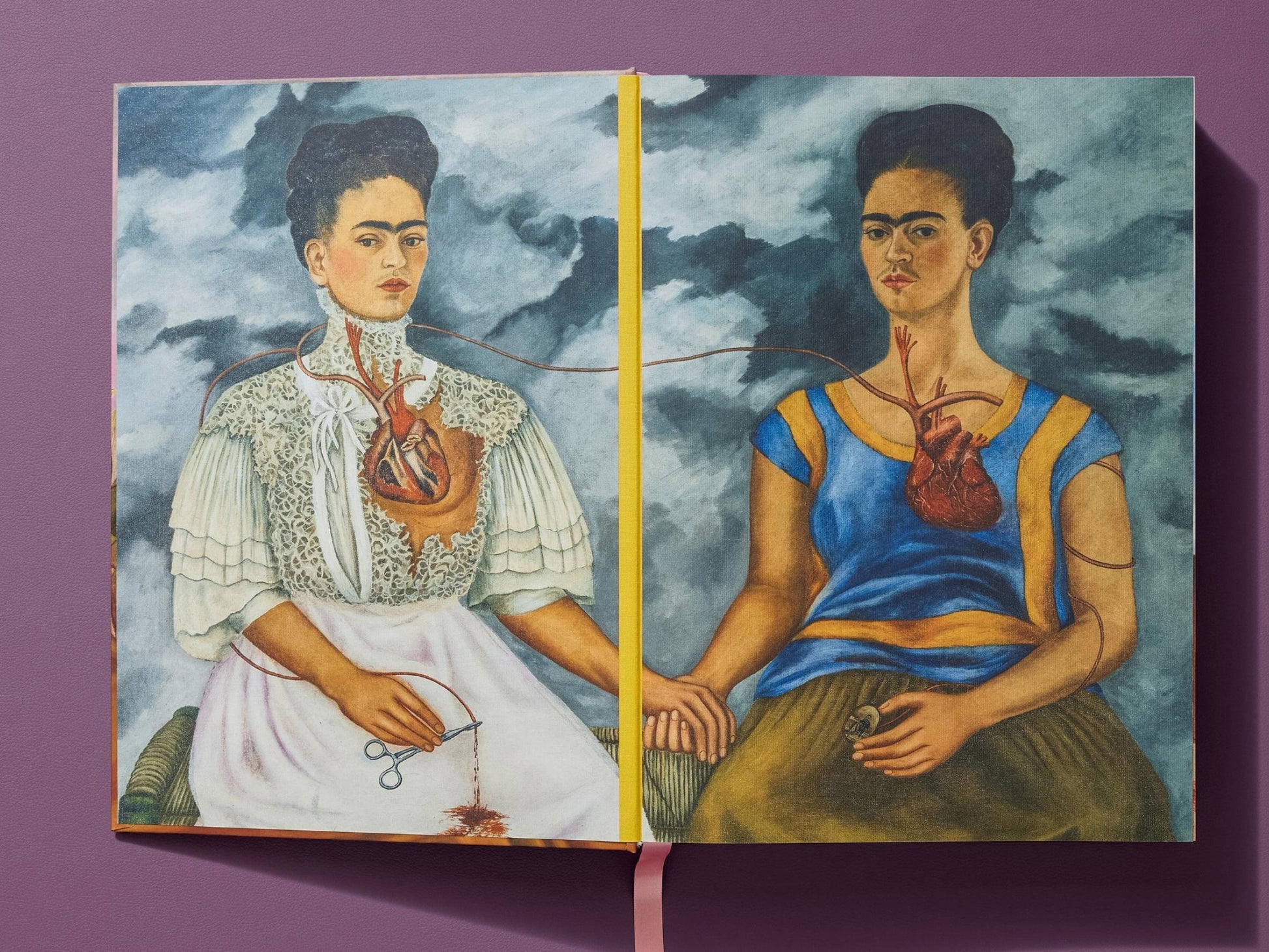 Open book spread from Frida Kahlo Complete Paintings showing The Two Fridas linked by a thread with a bloodied heart.