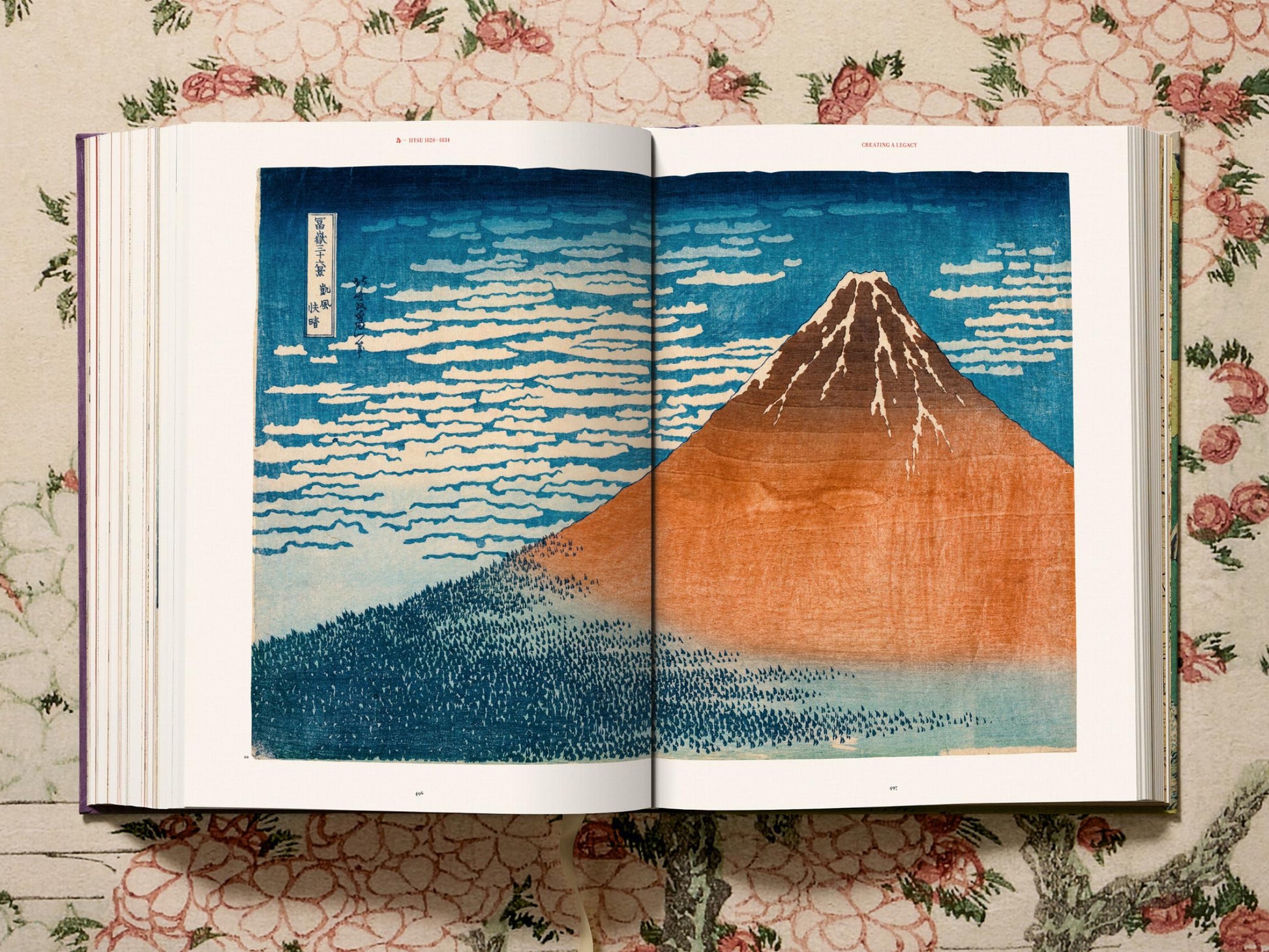 Open spread featuring a blue landscape print with Mount Fuji in orange against a deep blue sky and surrounding hills.
