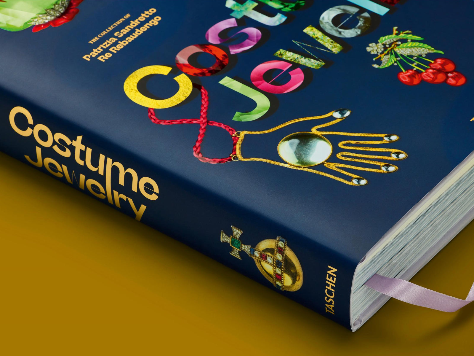 Angled close-up of the blue Costume Jewelry book showing its spine and a purple ribbon bookmark.