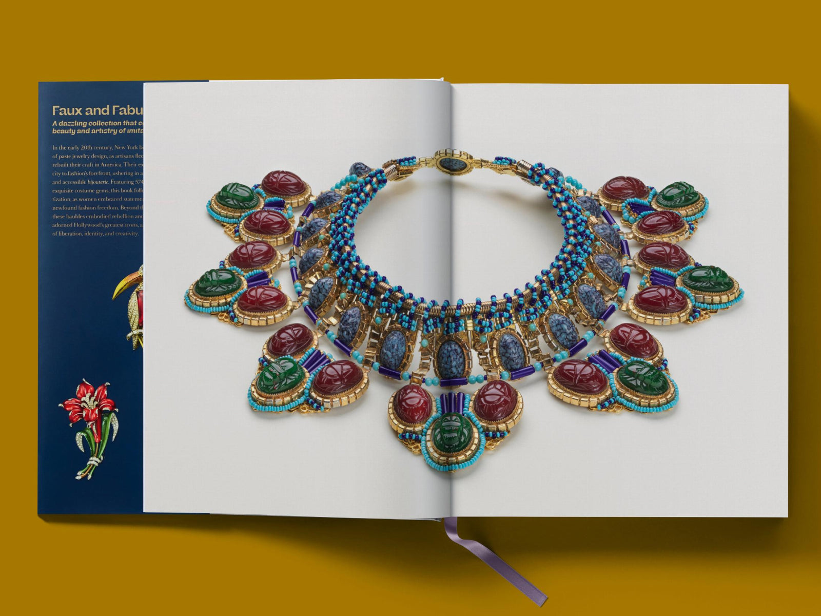 Double page spread featuring an ornate bejeweled necklace laid across white pages with blue margins.