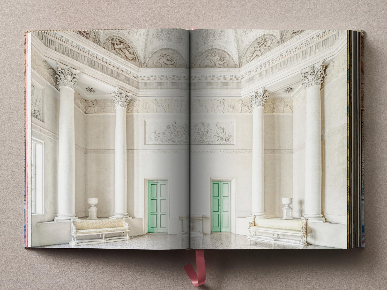 Palazzo Te interior with tall white columns, pale walls, and mint green doors between them