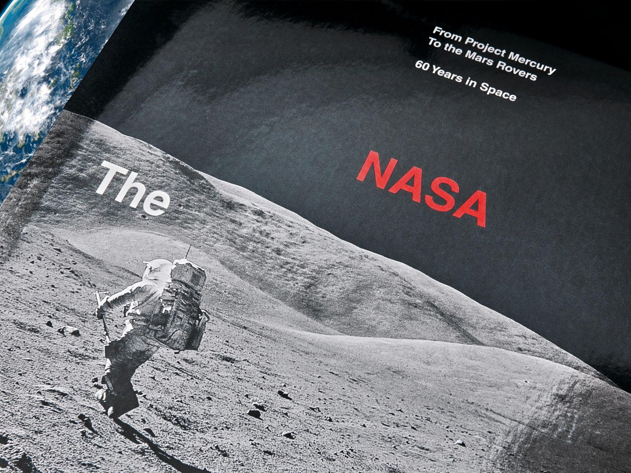 Close-up of The NASA Archives cover showing an astronaut on the moon with Earth visible in the background