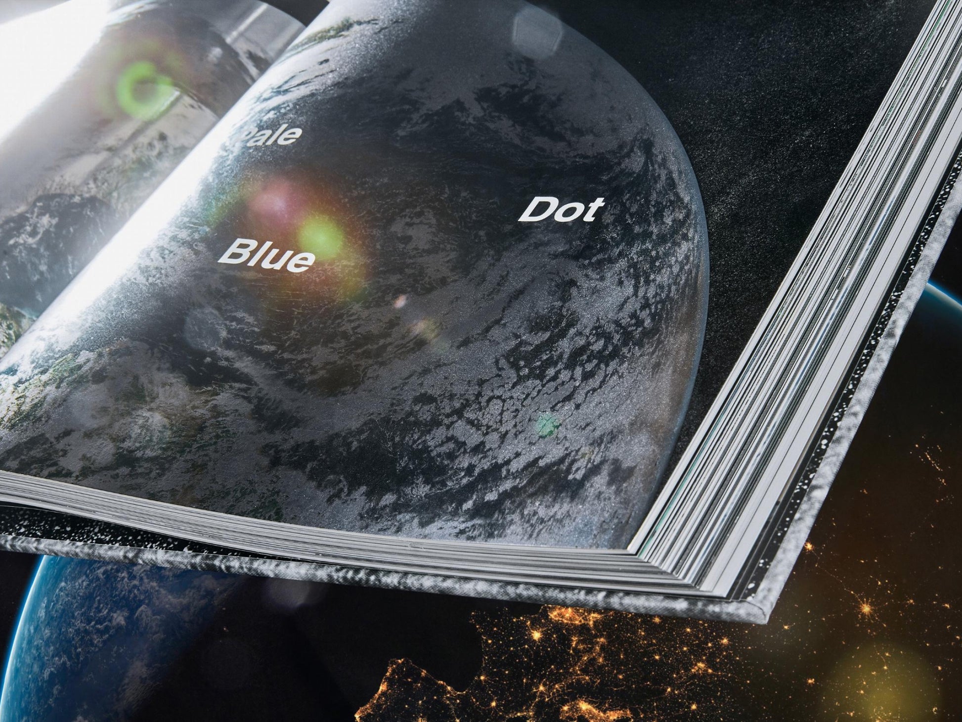 Curved open pages of The NASA Archives book showing Earth and the Blue Dot label