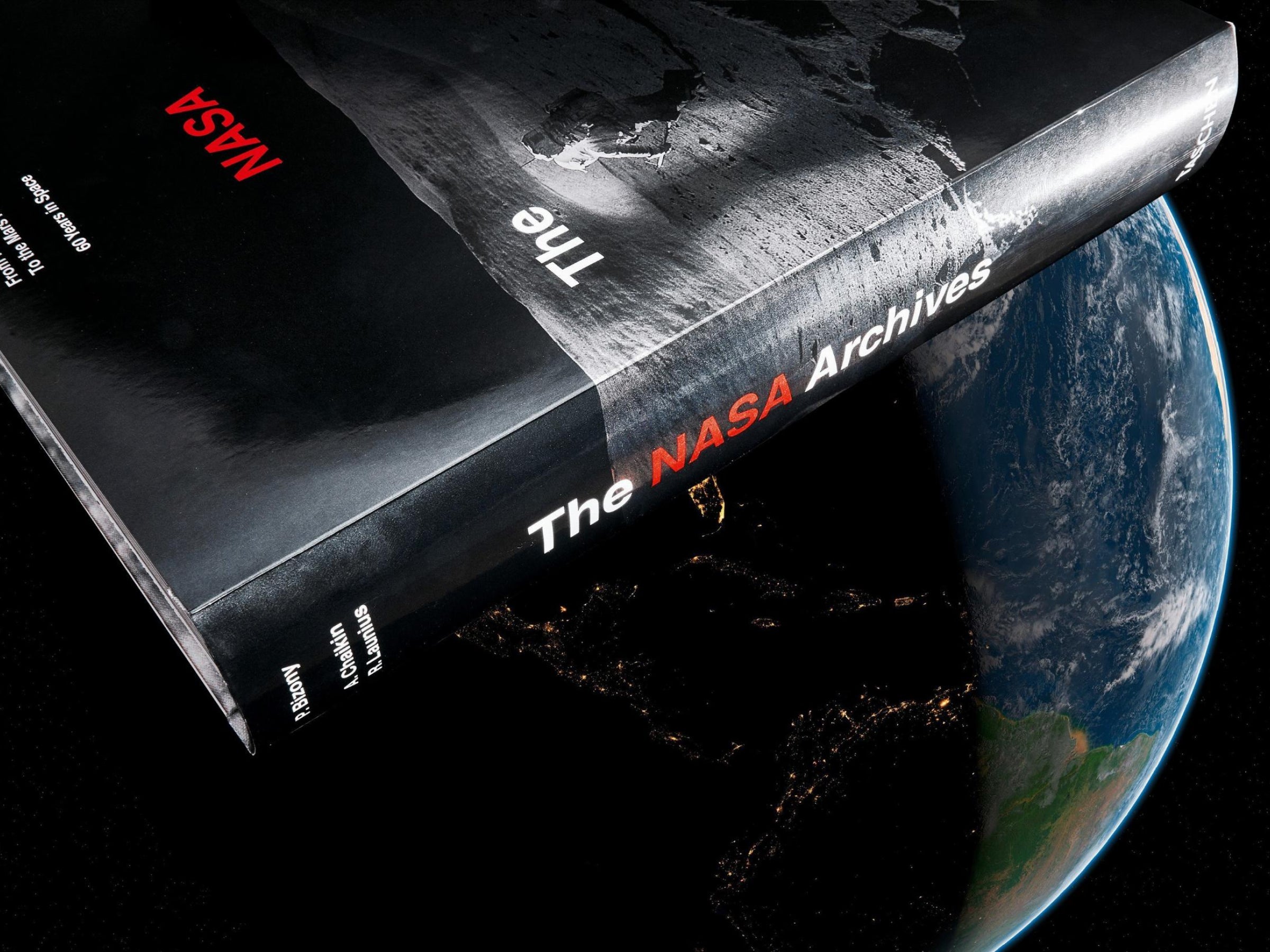 Tilted cover of The NASA Archives book over Earth