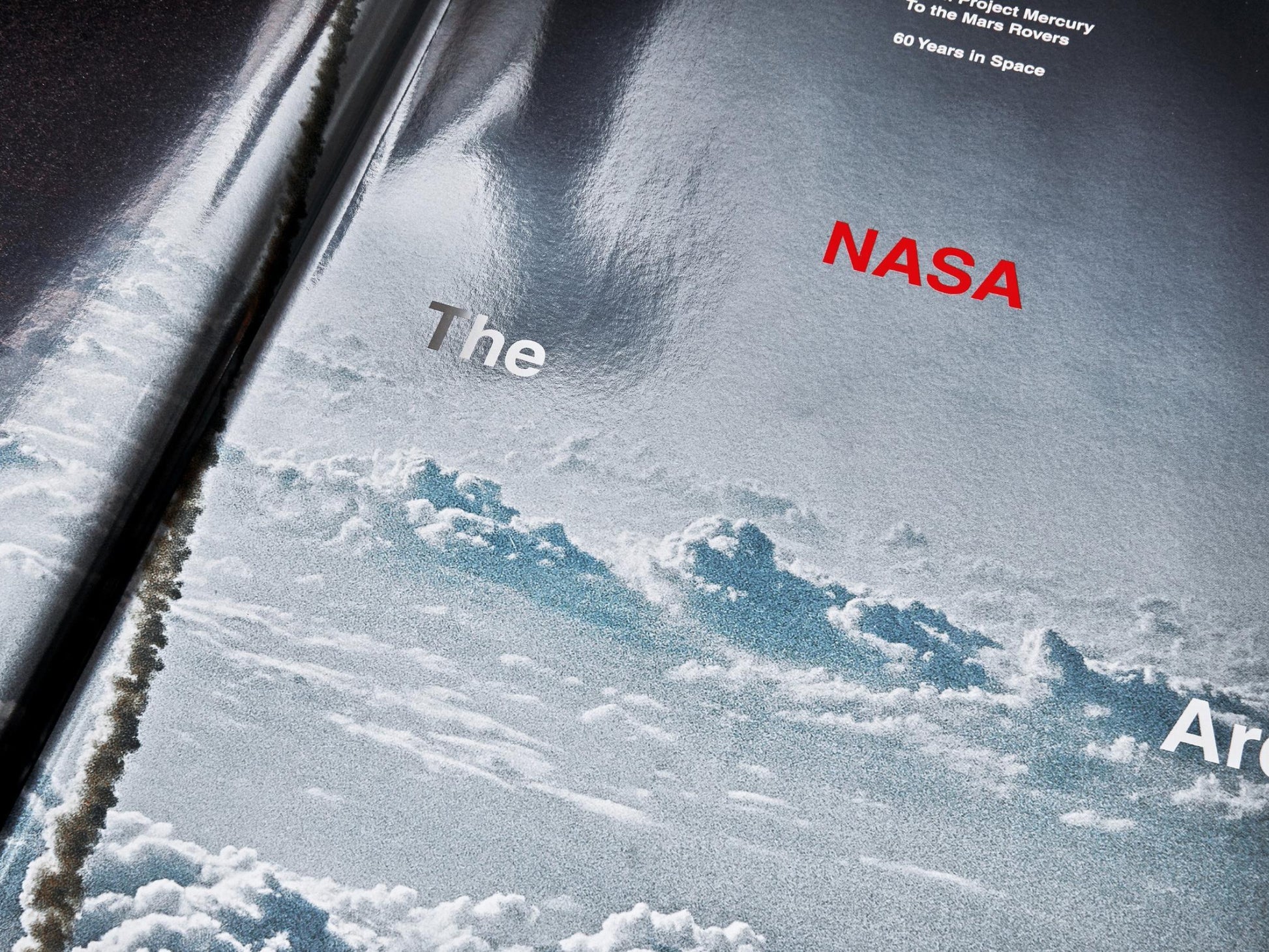 Angled view of The NASA Archives book with Earth in the background