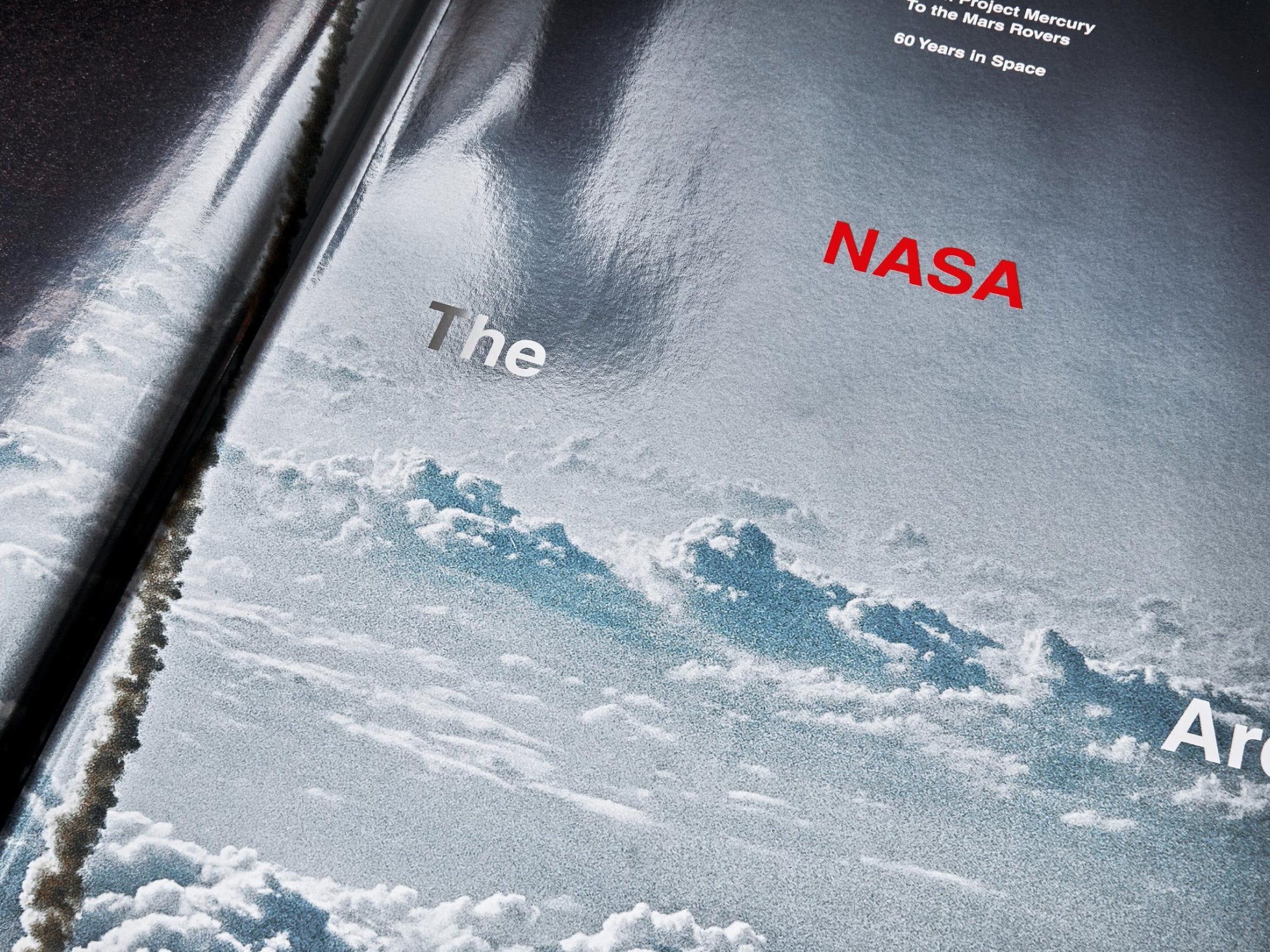 Angled view of The NASA Archives book with Earth in the background