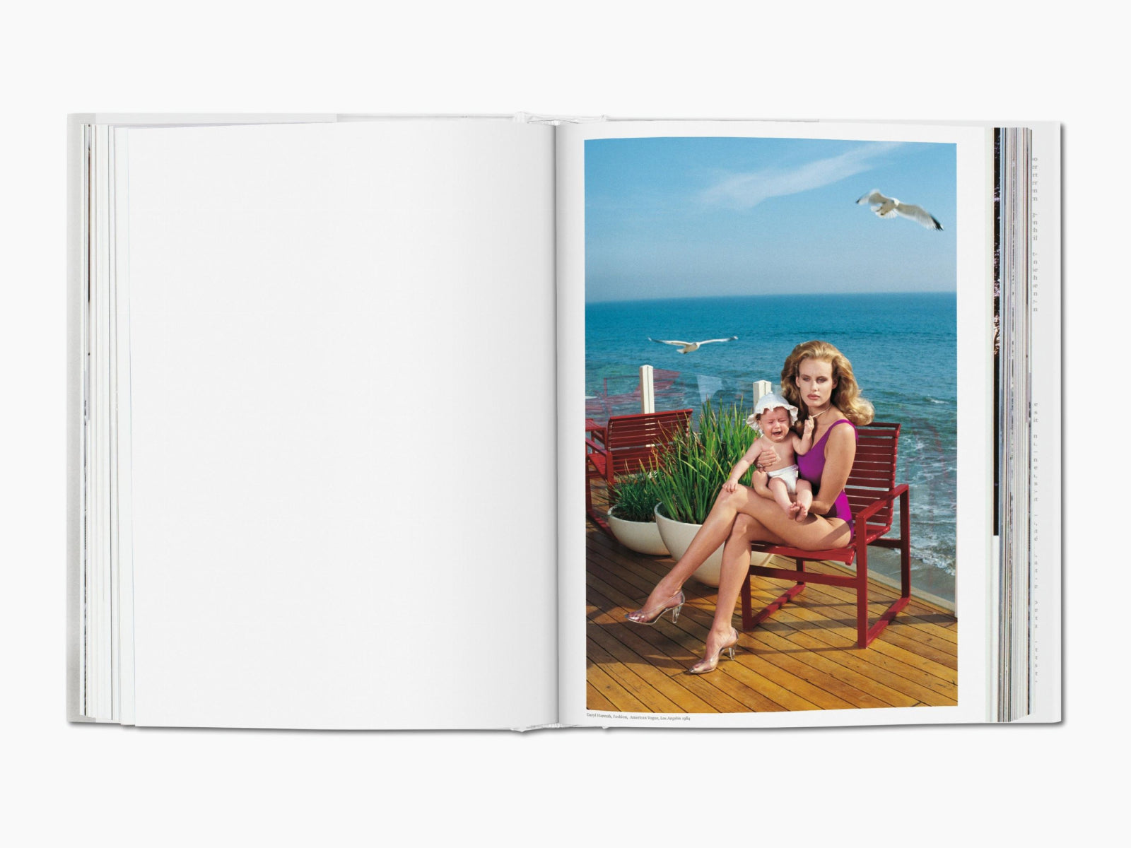 Spread from Helmut Newton SUMO showing a woman in a purple swimsuit with a baby on a wooden deck by the sea.
