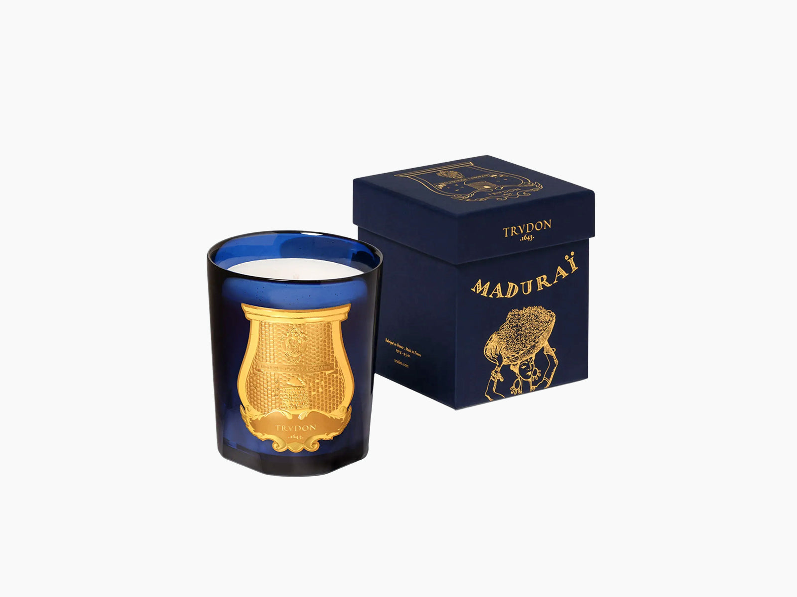 Blue glass candle holder with a gold ornate emblem beside a navy box labeled Maduraï Splendour of Indian Jasmine.