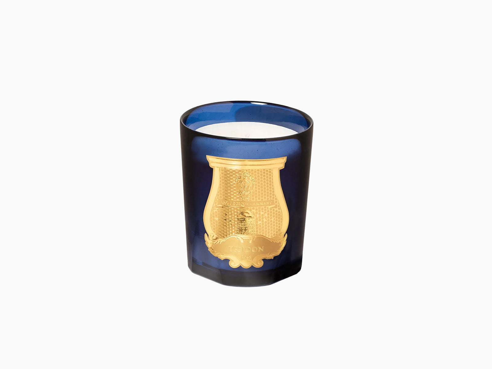 Blue glass candle holder with a gold emblem alone against a plain background