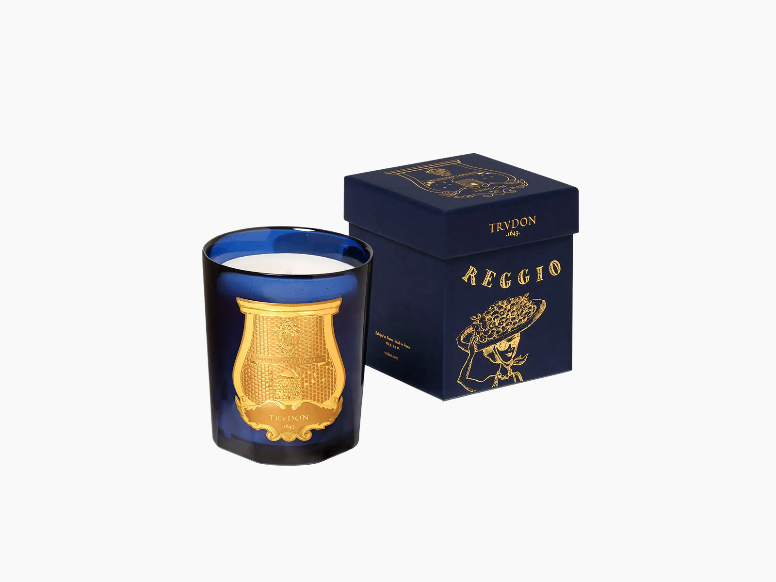 Blue glass candle with a gold crest beside a navy box featuring gold detailing.