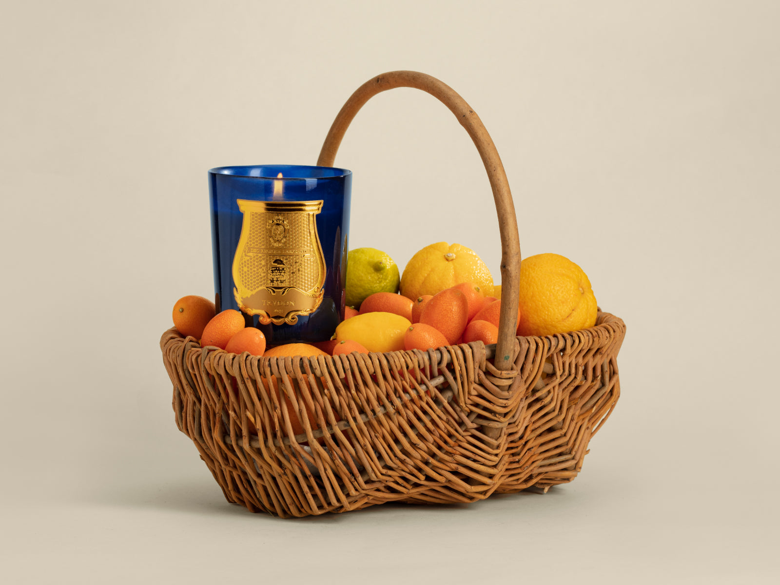 Basket of mandarins and lemons with a cobalt blue glass candle holder bearing a gold crest.