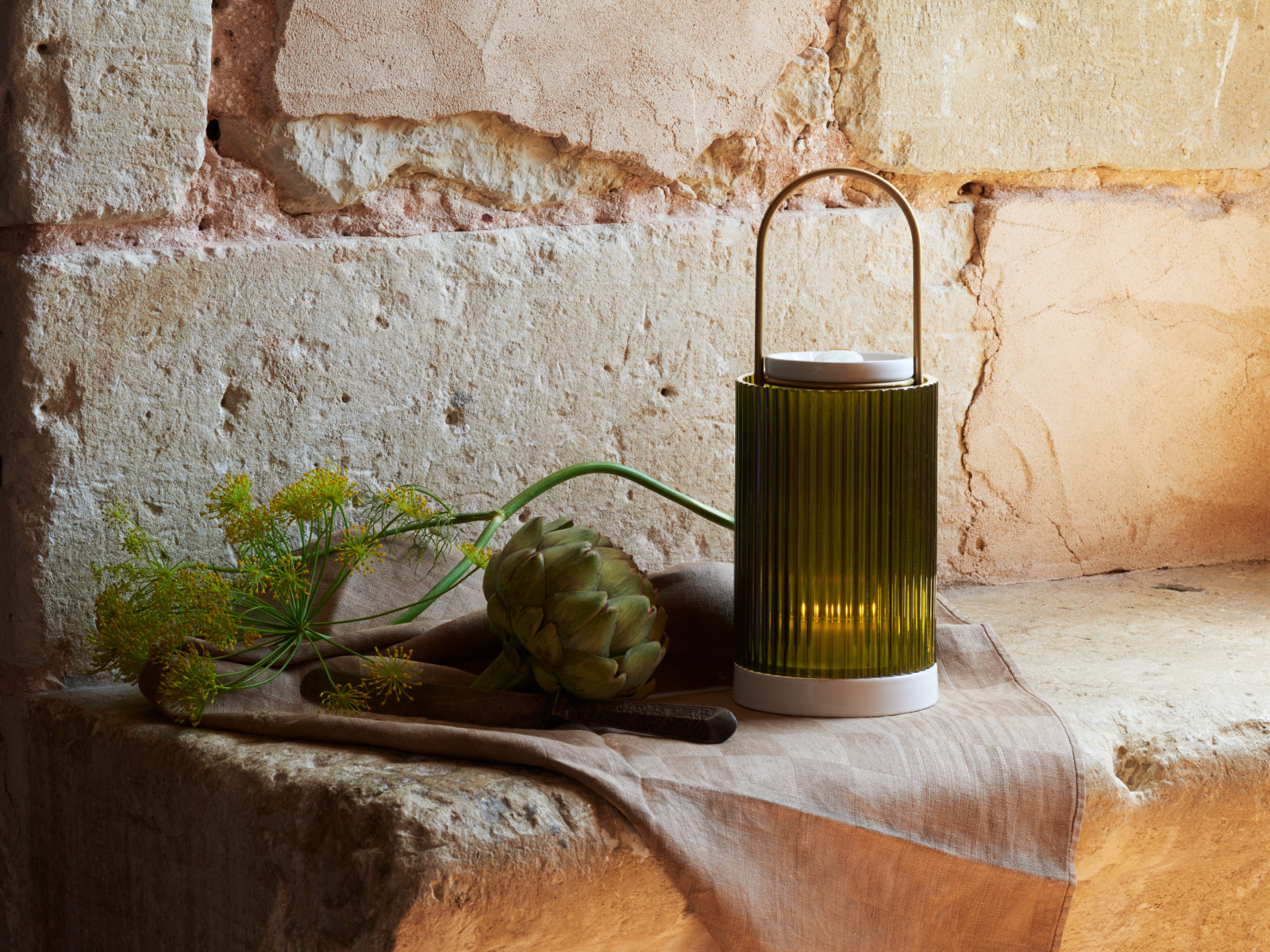 La Promeneuse The Object green ribbed ceramic diffuser with curved metal handle on linen beside an artichoke.