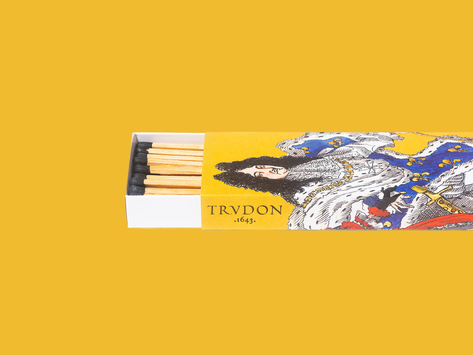 Scented matches in a decorative yellow box with an ornate king and queen illustration, white tray with matches visible.