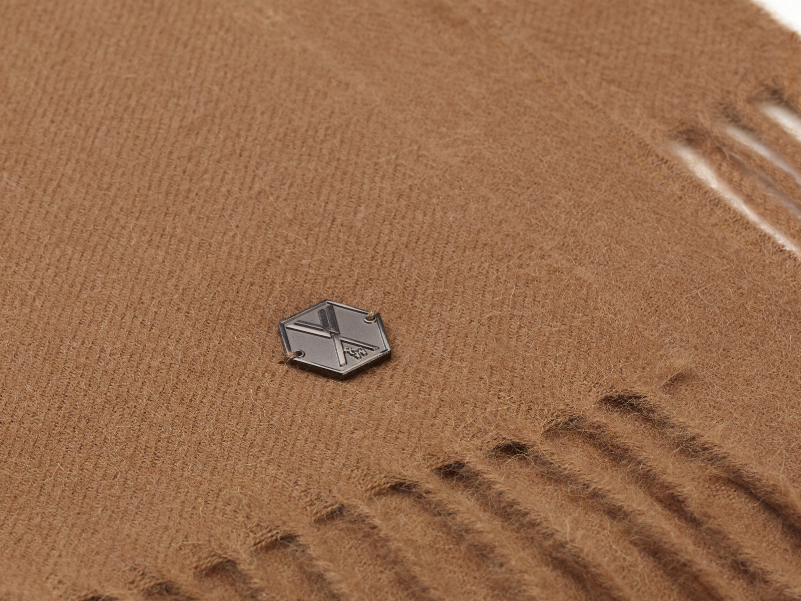 Close-up of brown alpaca blanket fabric with a small metal logo tag.