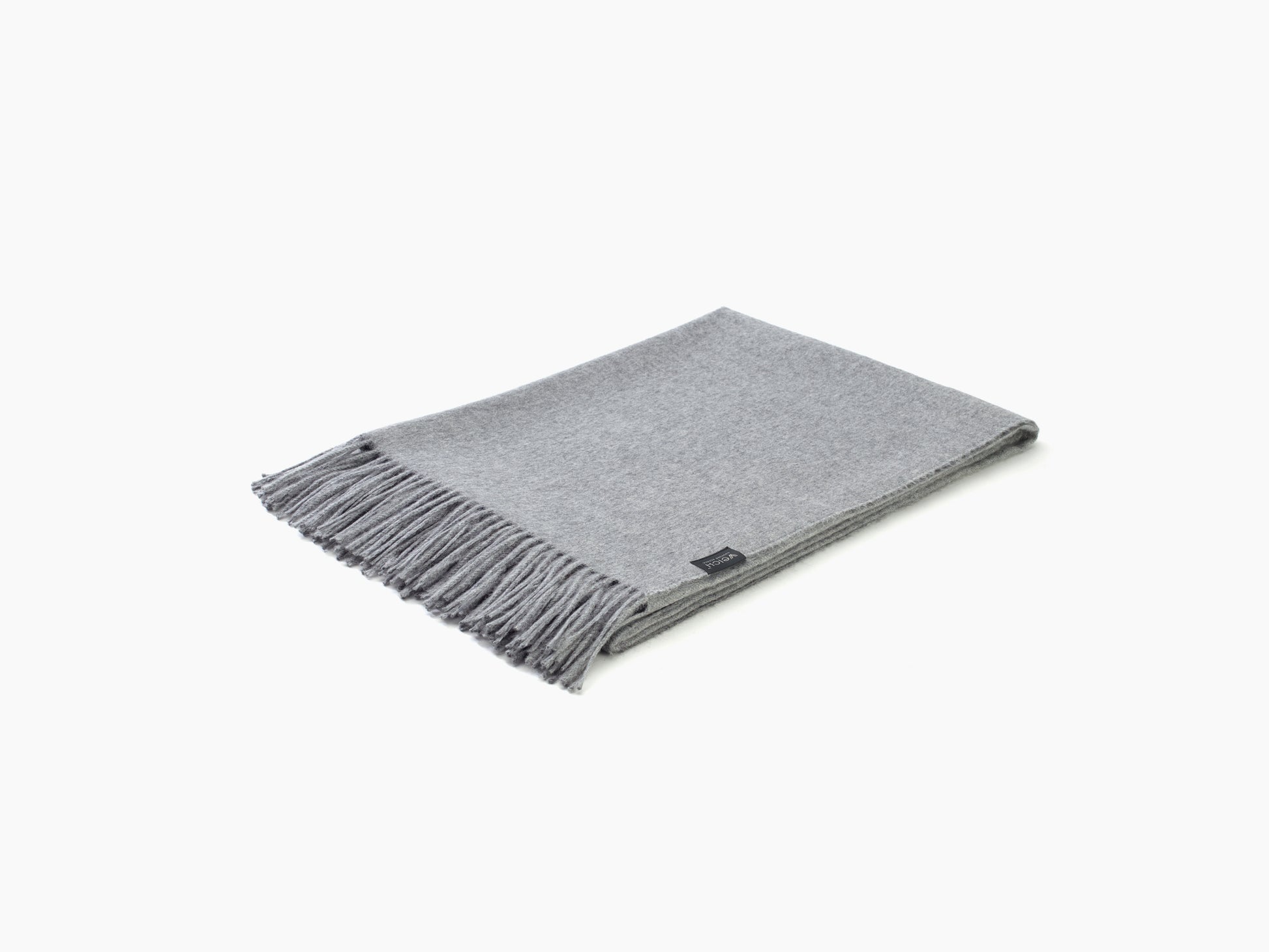 Plaid ALMA alpaca blanket in light gray with fringed edges folded on a white background