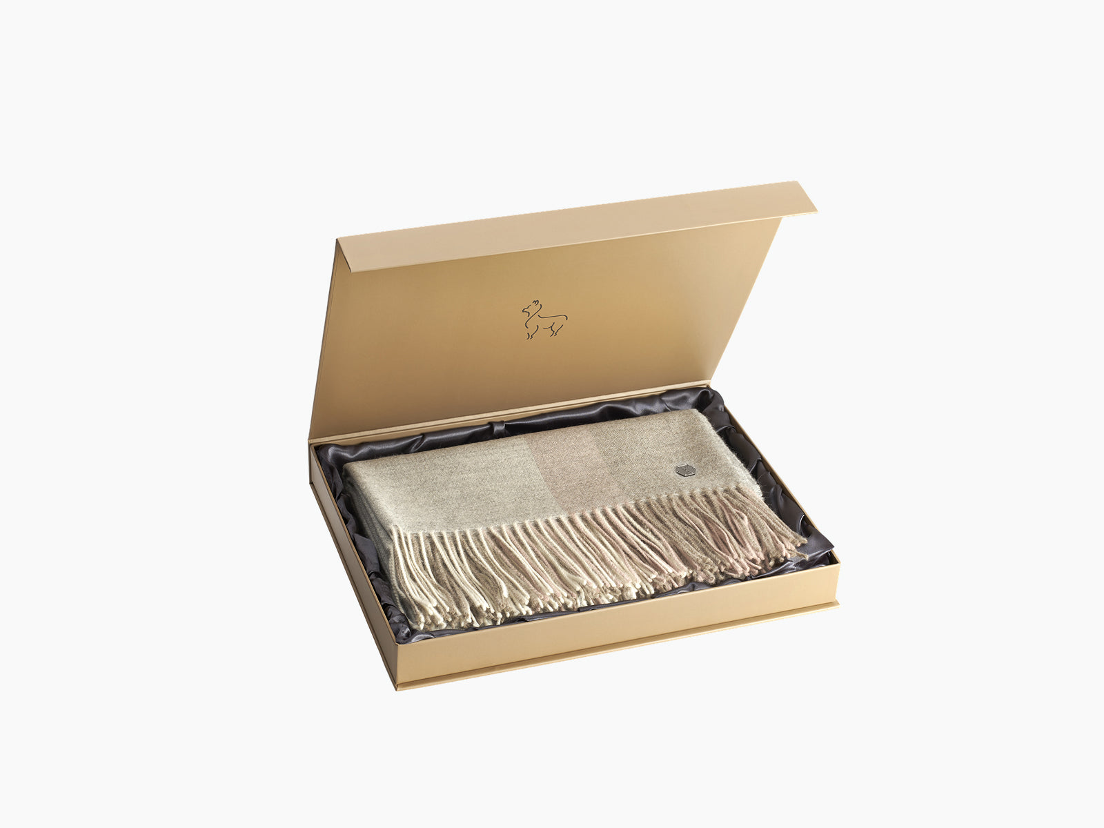 Open gift box reveals a soft beige throw with fringe tucked inside