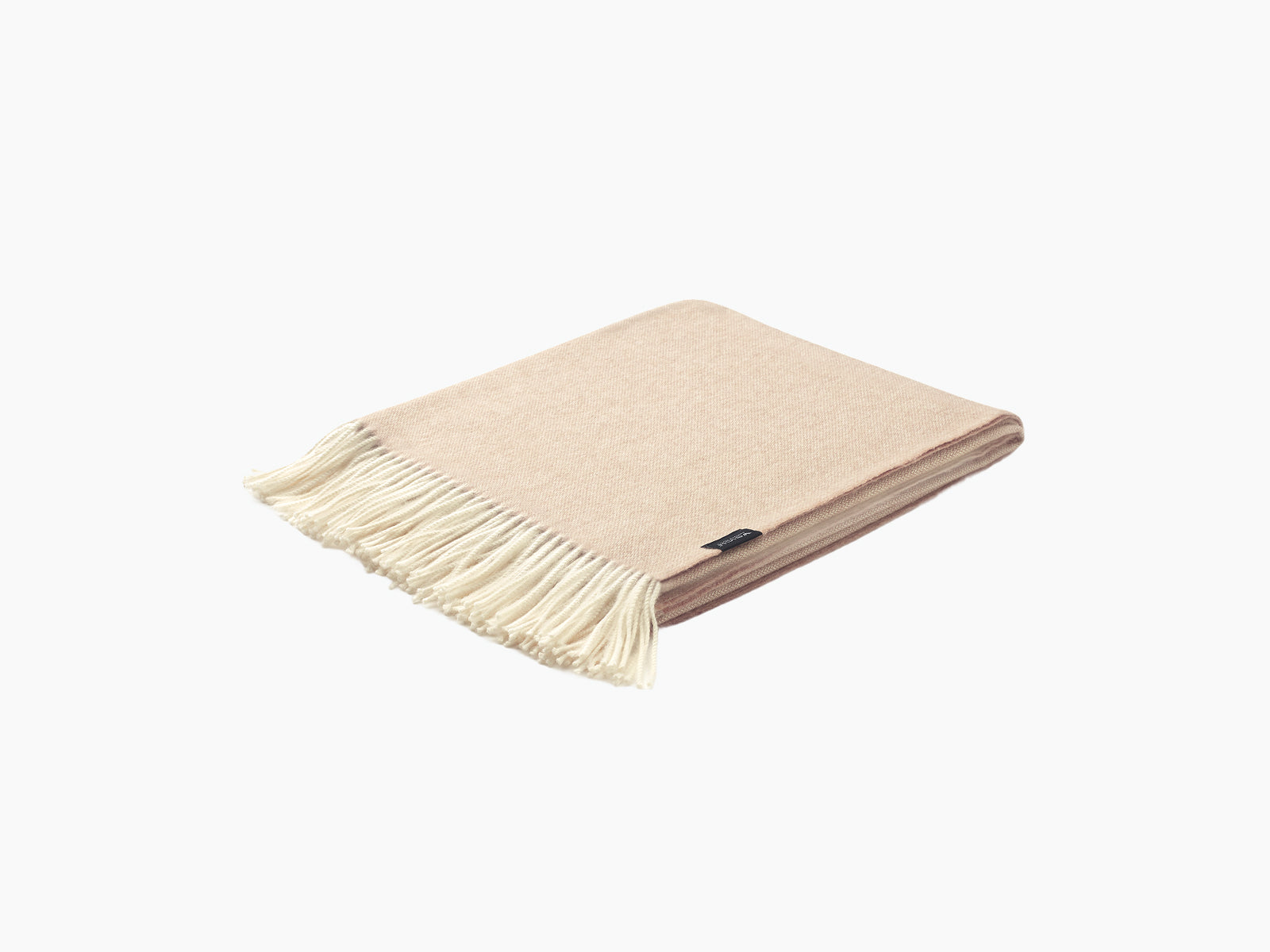 Soft pale beige plaid blanket folded with fringe along one edge