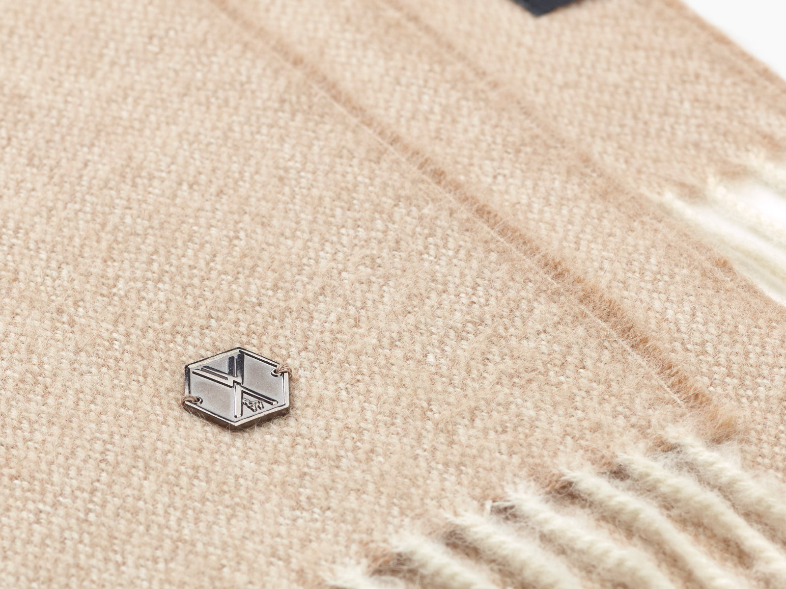 Beige alpaca plaid fabric with a small metal hex tag