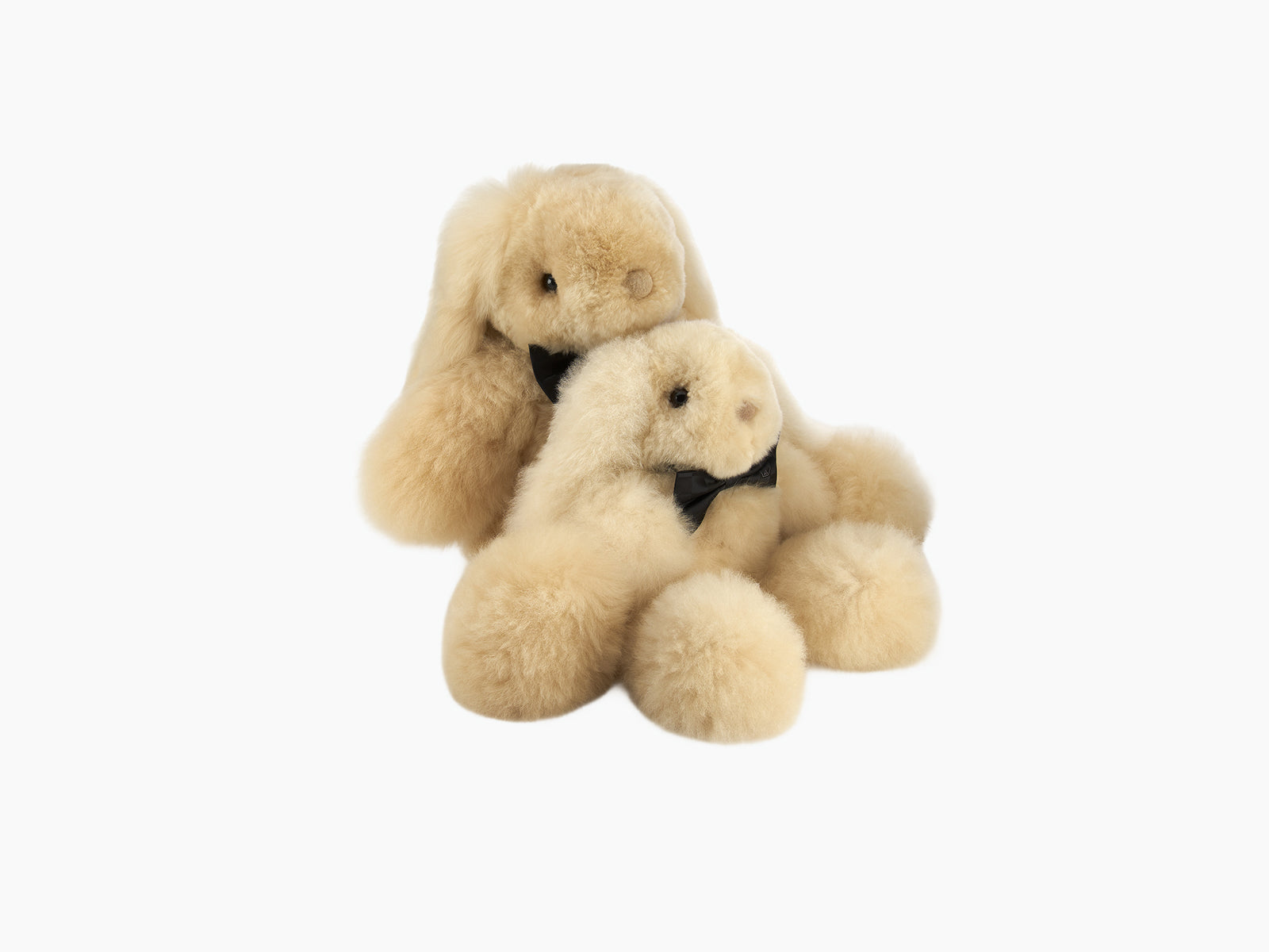 Two Milo rabbit plush toys in soft beige alpaca fur with black bow ties.