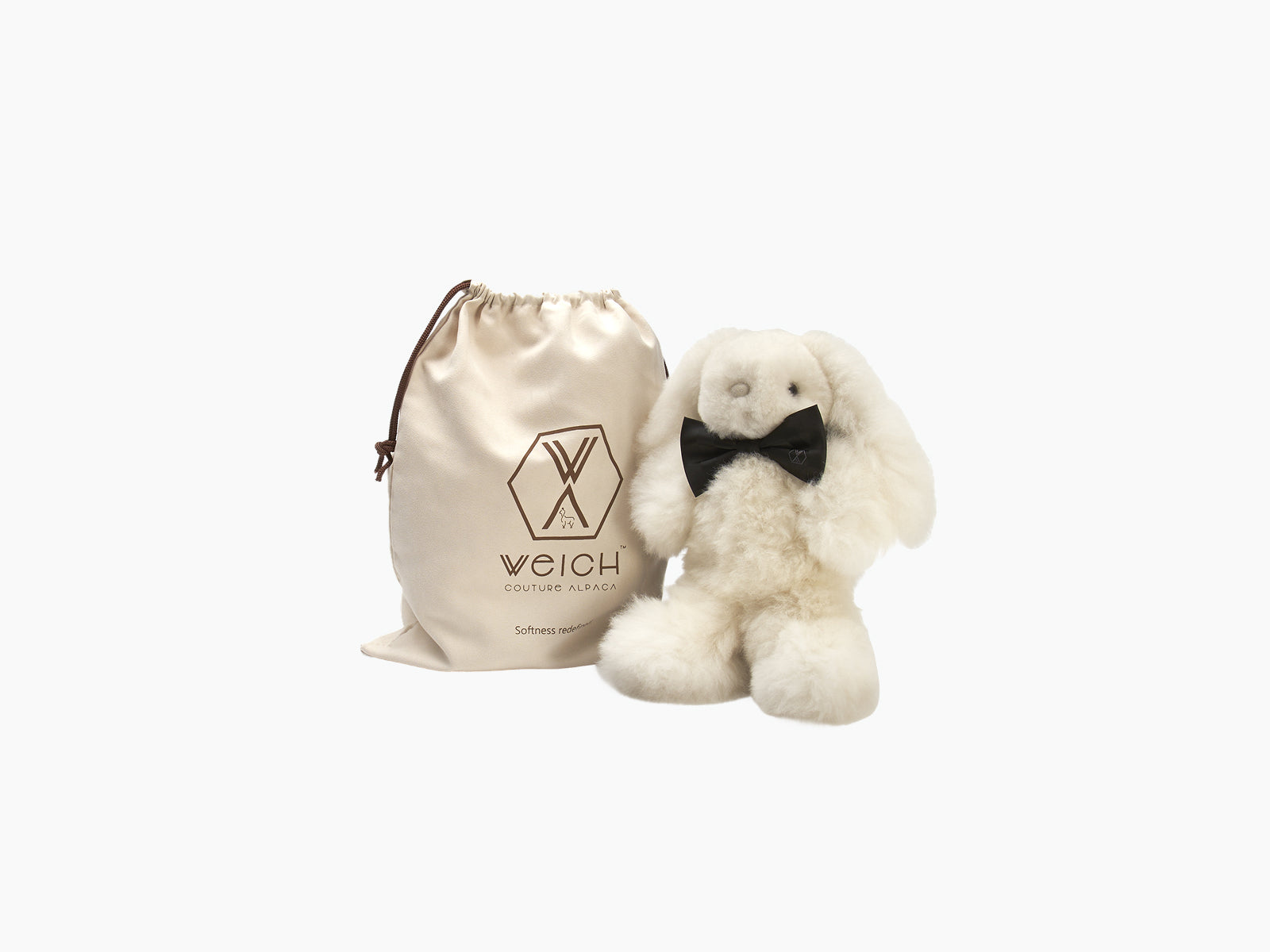 Ivory Milo rabbit plush with black bow tie beside beige WEICH bag.